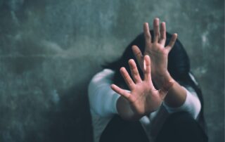 Scared woman raising her hands in self-defense against a threat.