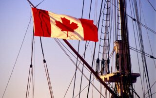The Canadian flag is flying on the mast of a ship.