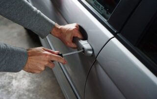 Person using a screwdriver to break into a car door.