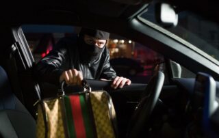 A masked person is stealing a handbag.