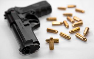 Handgun with scattered bullets around it.