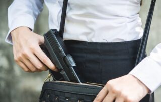 Young woman with concealed weapon gun in her small handbag.