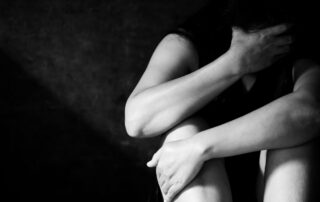 Distressed woman sitting with head in hand.