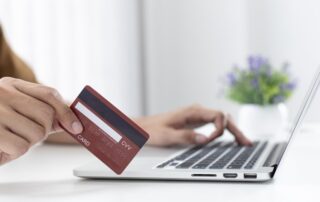 A person holding a credit card while using a laptop.