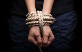 A person’s hands are tied tightly with a rope.