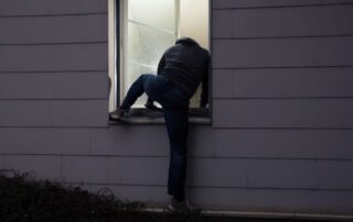 Person climbing through a house window.