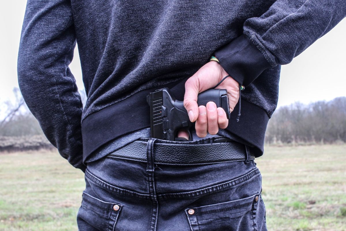 Person hiding a handgun in the waistband. Person hiding a handgun in the waistband.